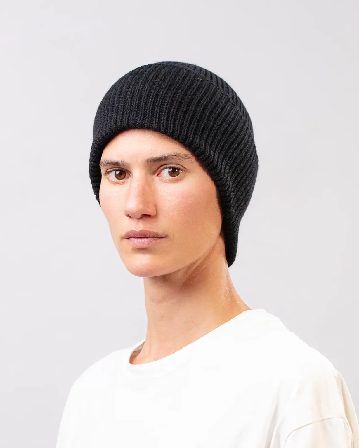 Photographie studio Bonnet Cachemire Régénéré Noir, porté par un mannequin Femme. Ce bonnet est fabriqué en France, à partir de Laine et de Cachemire Recyclé, par la marque haut-de-gamme Maison Douillet. Cest un modèle pour Homme et Femme.