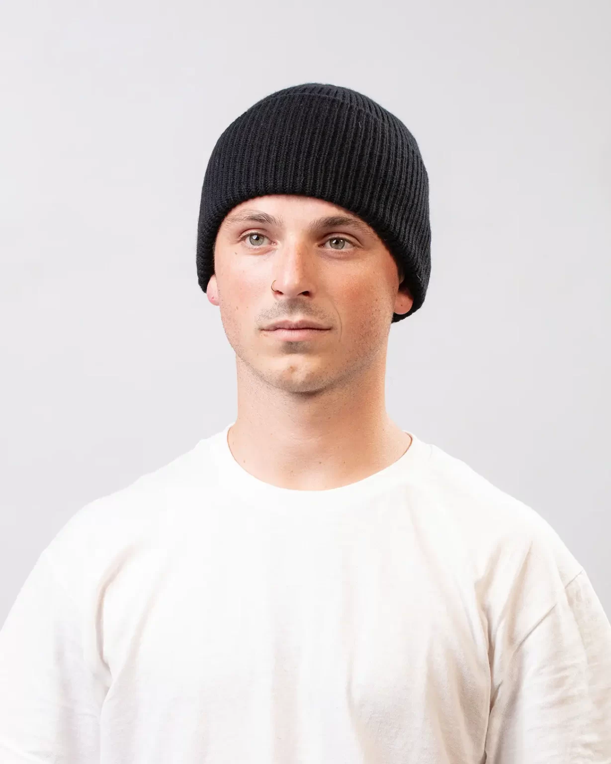 Photographie studio Bonnet Cachemire Régénéré Noir, porté par un mannequin Homme. Ce bonnet est fabriqué en France, à partir de Laine et de Cachemire Recyclé, par la marque haut-de-gamme Maison Douillet. Cest un modèle pour Homme et Femme.