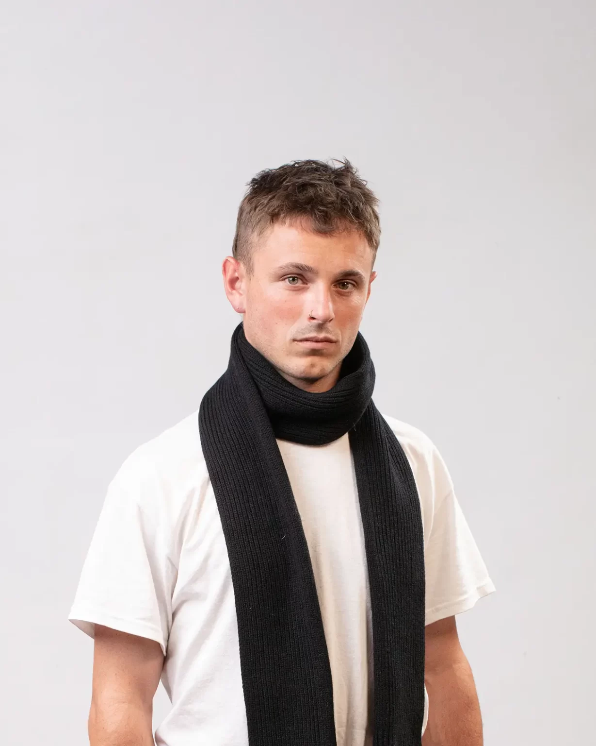 Photographie studio de l'Echarpe Cachemire Régénéré Noir, porté par un mannequin Homme. Cette écharpe est fabriqué en France, à partir de Laine et de Cachemire Recyclé, par la marque haut-de-gamme Maison Douillet. Cest un modèle pour Homme et Femme.