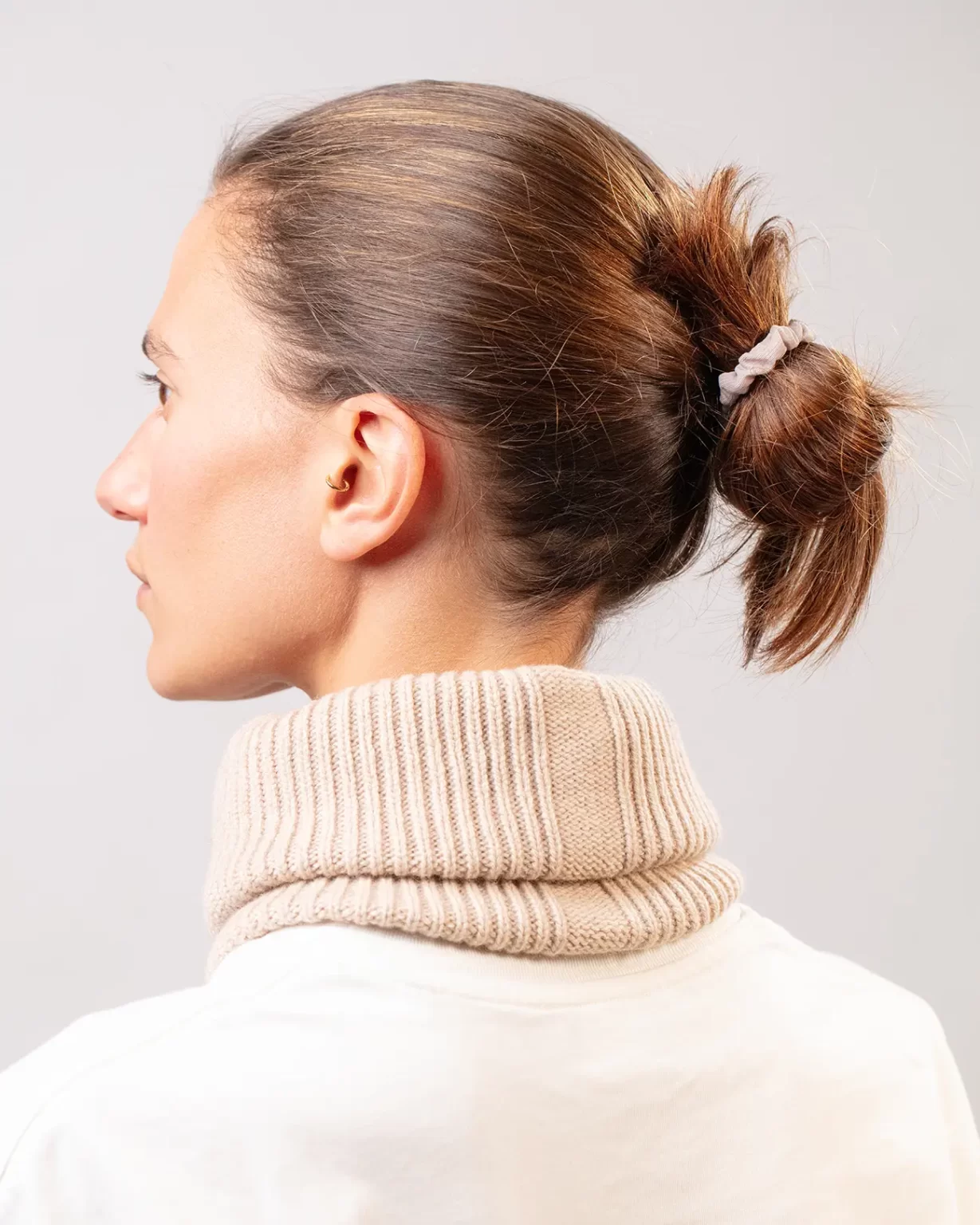 Photographie studio en détail du dos du Tour de Cou Cachemire Régénéré Beige, porté par un mannequin Femme. Ce tour de cou est fabriqué en France, à partir de Laine et de Cachemire Recyclé, par la marque haut-de-gamme Maison Douillet. Cest un modèle pour Homme, Femme et Enfant.