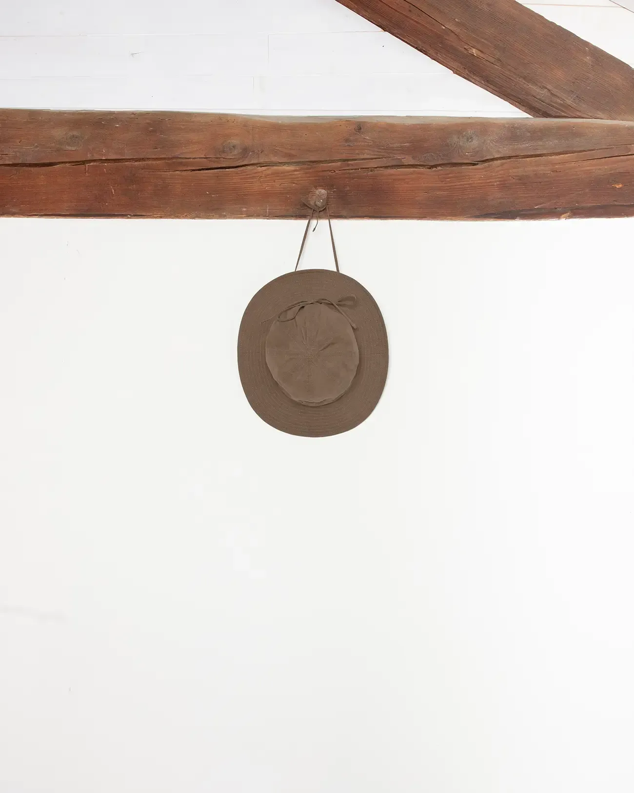 Chapeau marron de la marque Maison Douillet pour homme et femme en coton déperlant biologique. Photo produit prise en studio avec élément de décors en bois rappelant les Alpes.